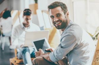 Smiling man holding a tablet in a bright office