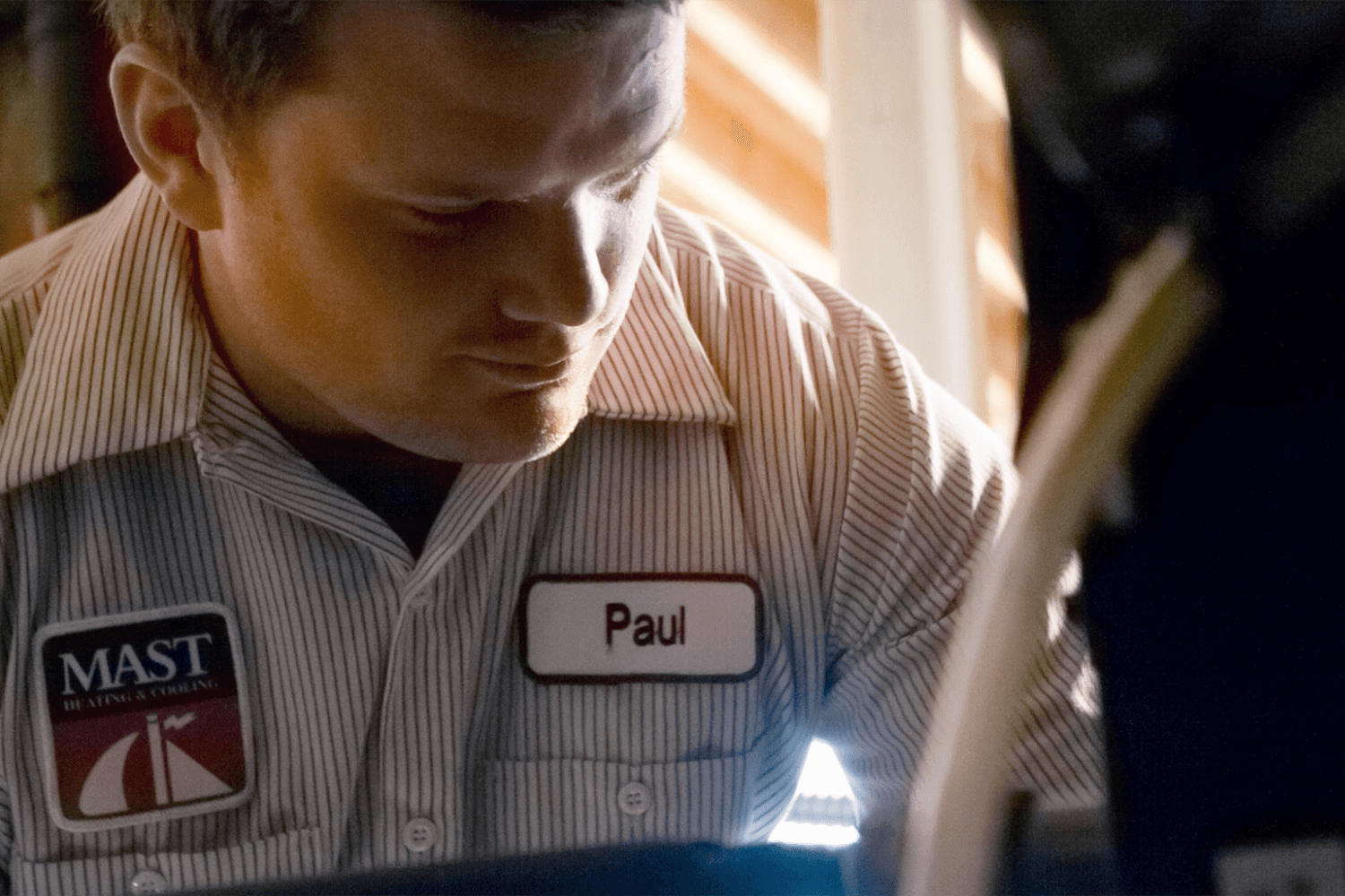 a Mast Heating & Cooling technician in Zeeland studying a piece of equipment