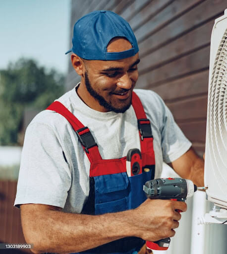 HVAC technician using a cordless drill to service an outdoor air conditioner condenser